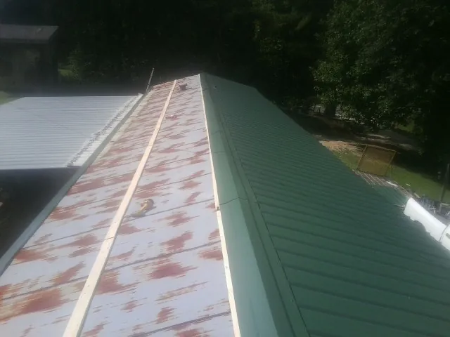 Old rusted panels beside newly installed green metal roofing — Wind Damage Roof Repair by Roofing Brothers in Wingdale