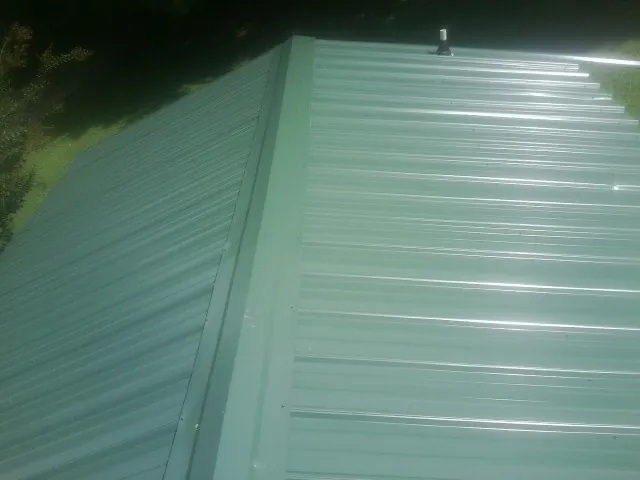 New green metal panels meeting at the ridge of a roof — Flat Roof Repair work by our crew in Wingdale