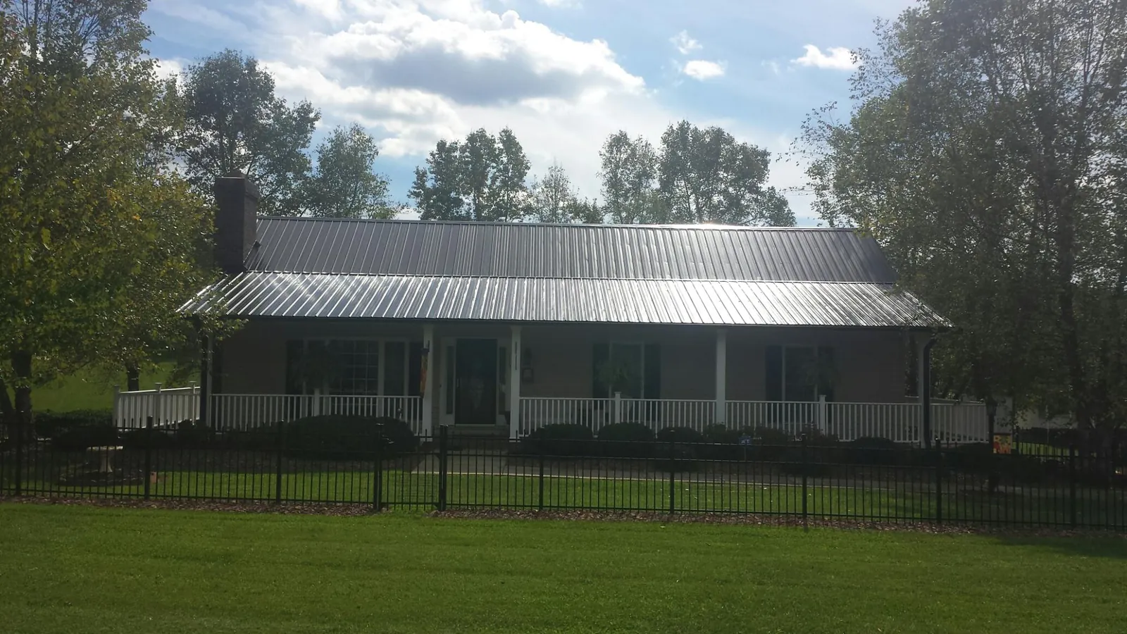 Gray metal roof on a brick ranch with a full width front porch — Gutter Guard Installation work by our crew in Wingdale