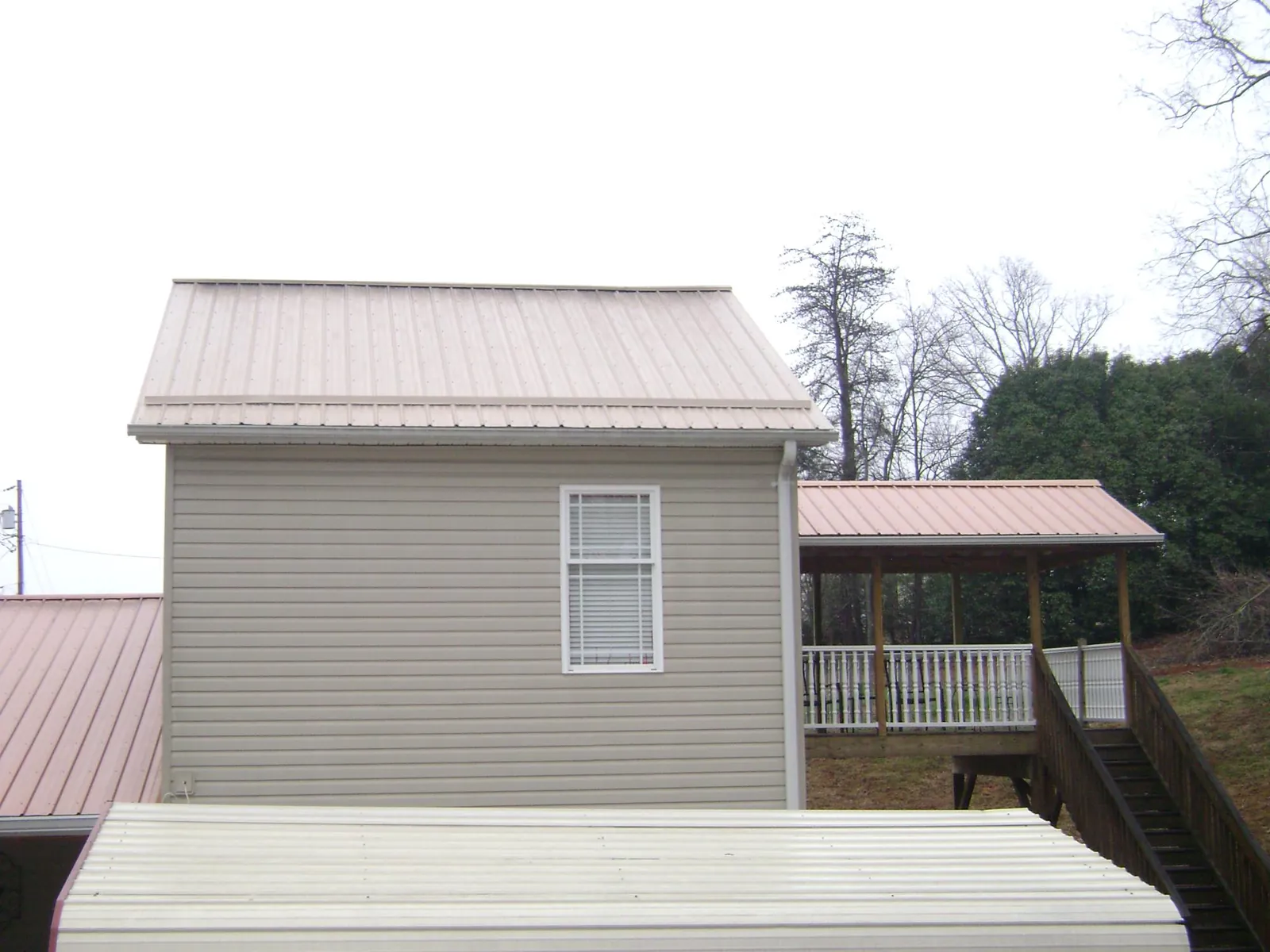 Tan metal roofs on a two story addition and attached porch, from a Roof Replacement job in Wingdale