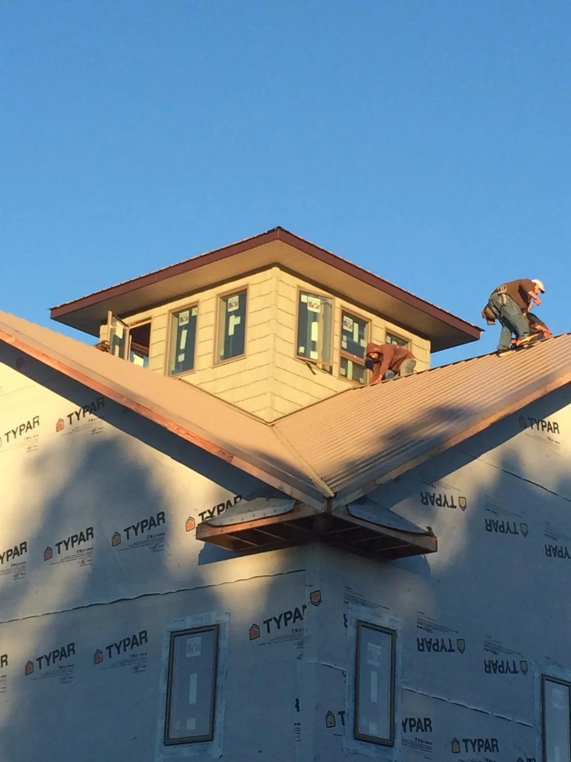 Roofers working around a rooftop cupola on a new metal roof at sunset — Roof Waterproofing in Wingdale by Roofing Brothers